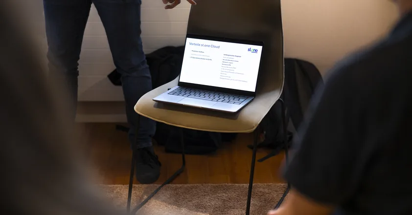Laptop mit einer Präsentationsfolie auf einem Stuhl im Workshop-Raum