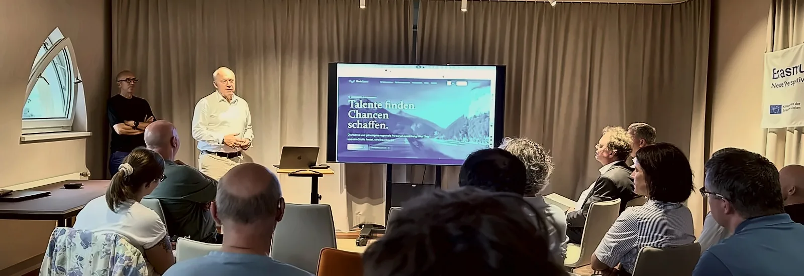 Vortrag beim KI-Café von MMIND.ai: Publikum vor einem Bildschirm mit der Website von RheinTalent